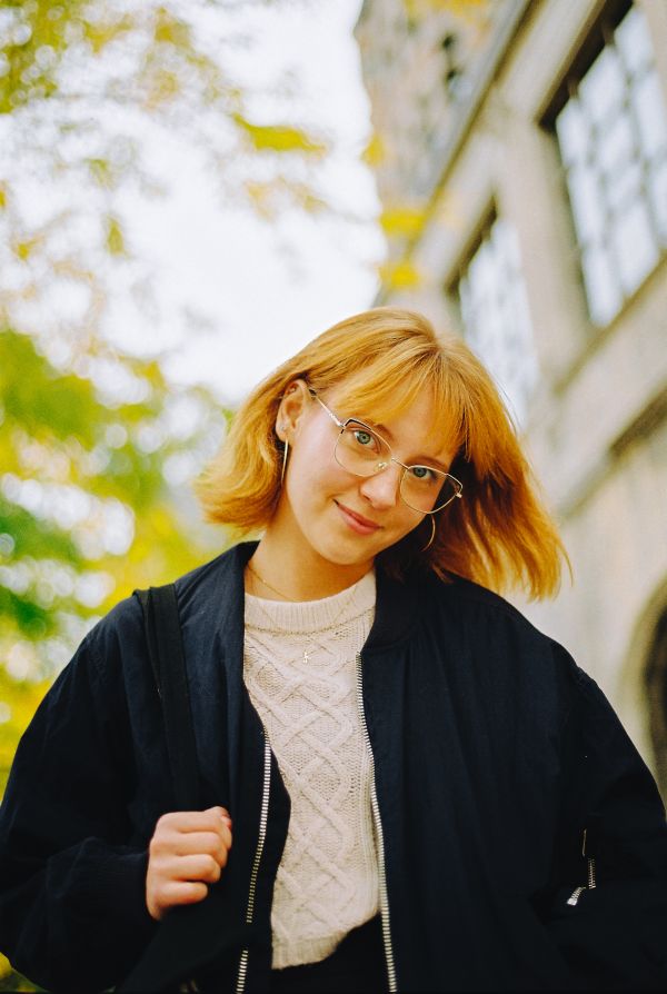 Alisa standing outside with a building and tree behind her