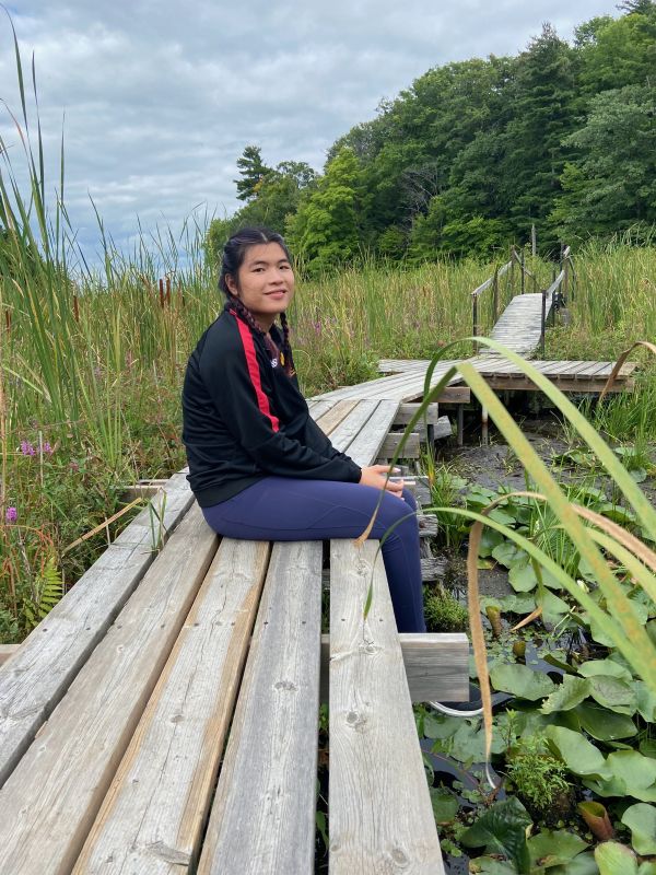 Charlotte sitting on a boardwalk in a wetland