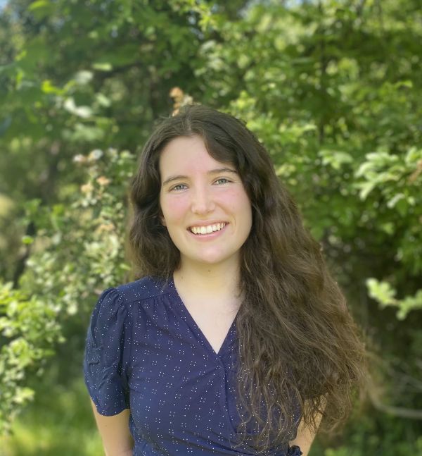 Portrait of Ember standing in front of trees