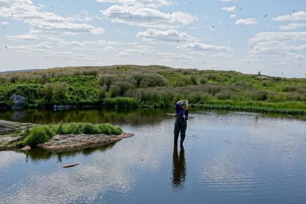 Zoe (student) standing in a pond holding up sediment core 