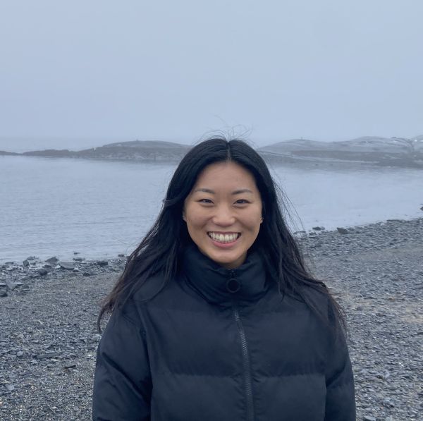 Jihyun at a shore line with rocky shore in the distance