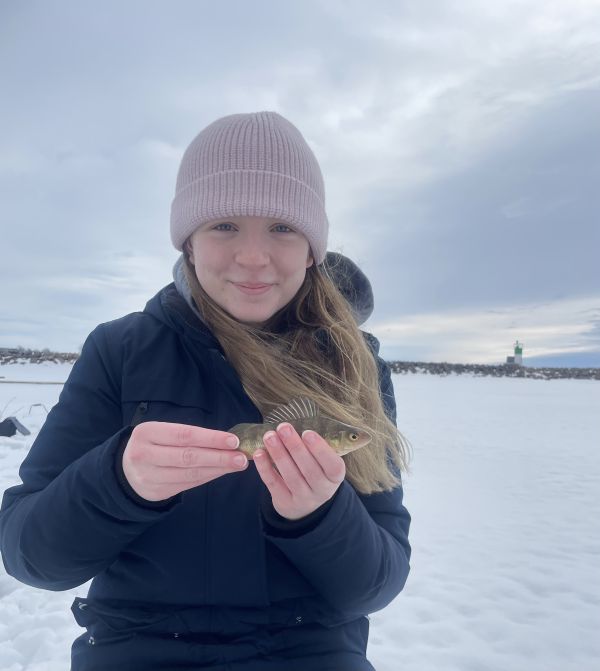 Maddigan on a frozen lake holding a small fish