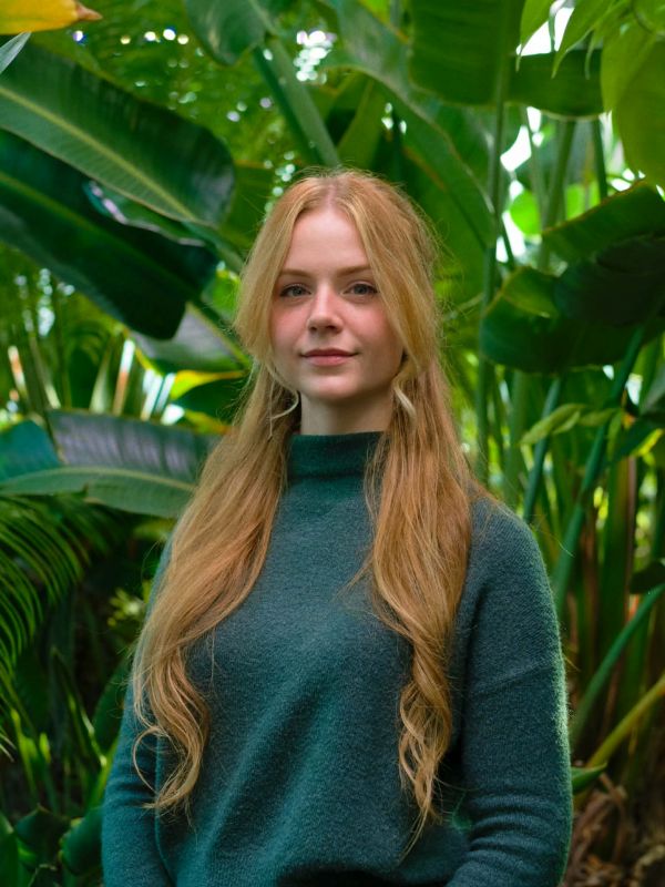 Shannon standing in front of leavy foliage