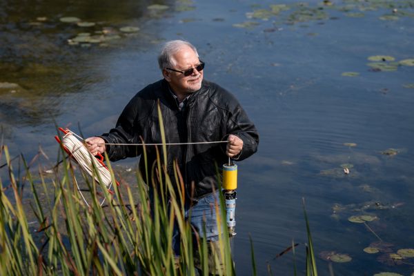 Dr. John Smol standing in a lake holding a sediment corer