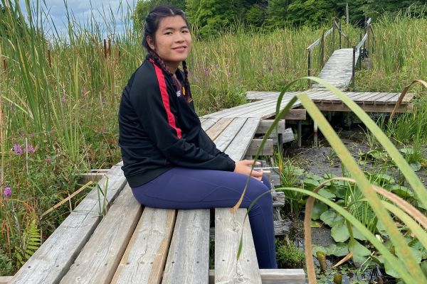 Charlotte sitting on a boardwalk in a wetland