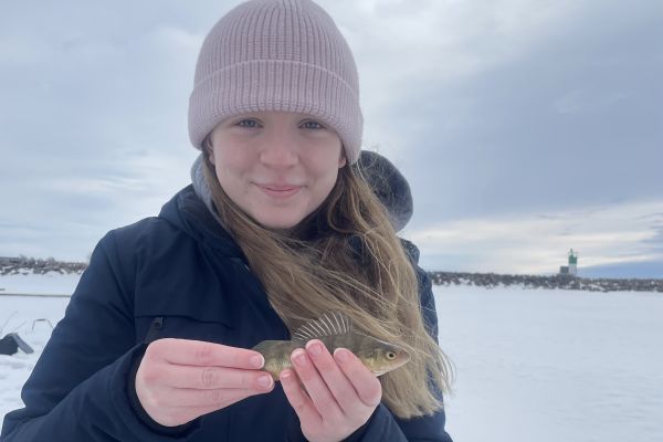 Maddigan on a frozen lake holding a small fish