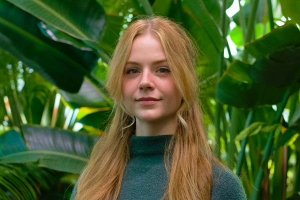 Shannon standing in front of leavy foliage